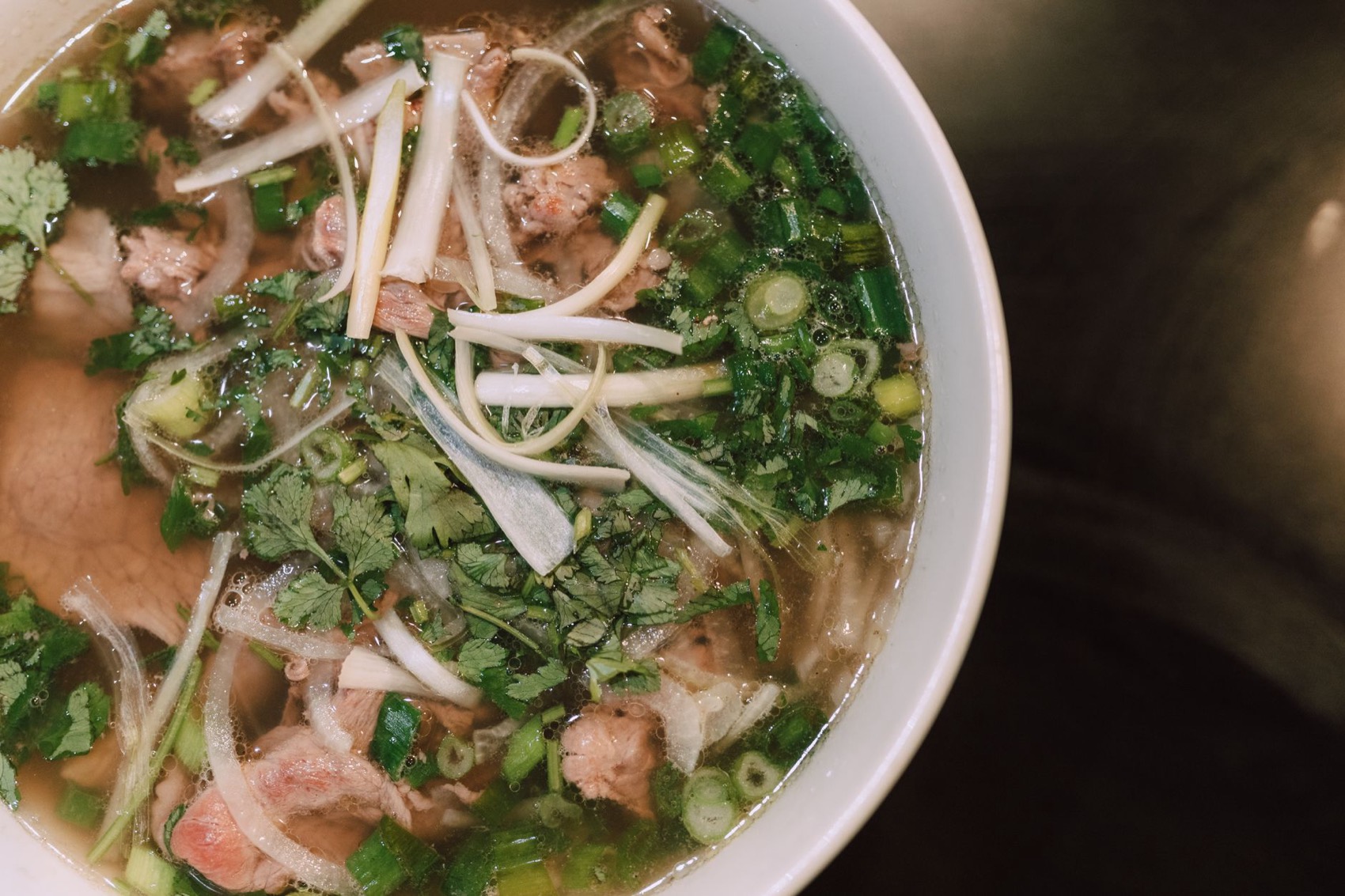 En færdig skål phở set ovenfra med urter og oksekød
